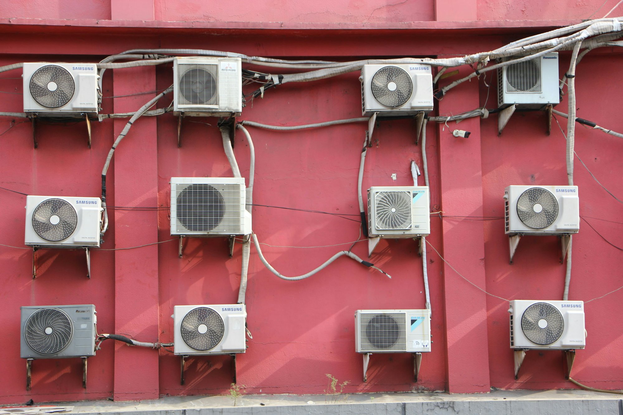 Multiple Samsung and Daikin outdoor AC units on building wall