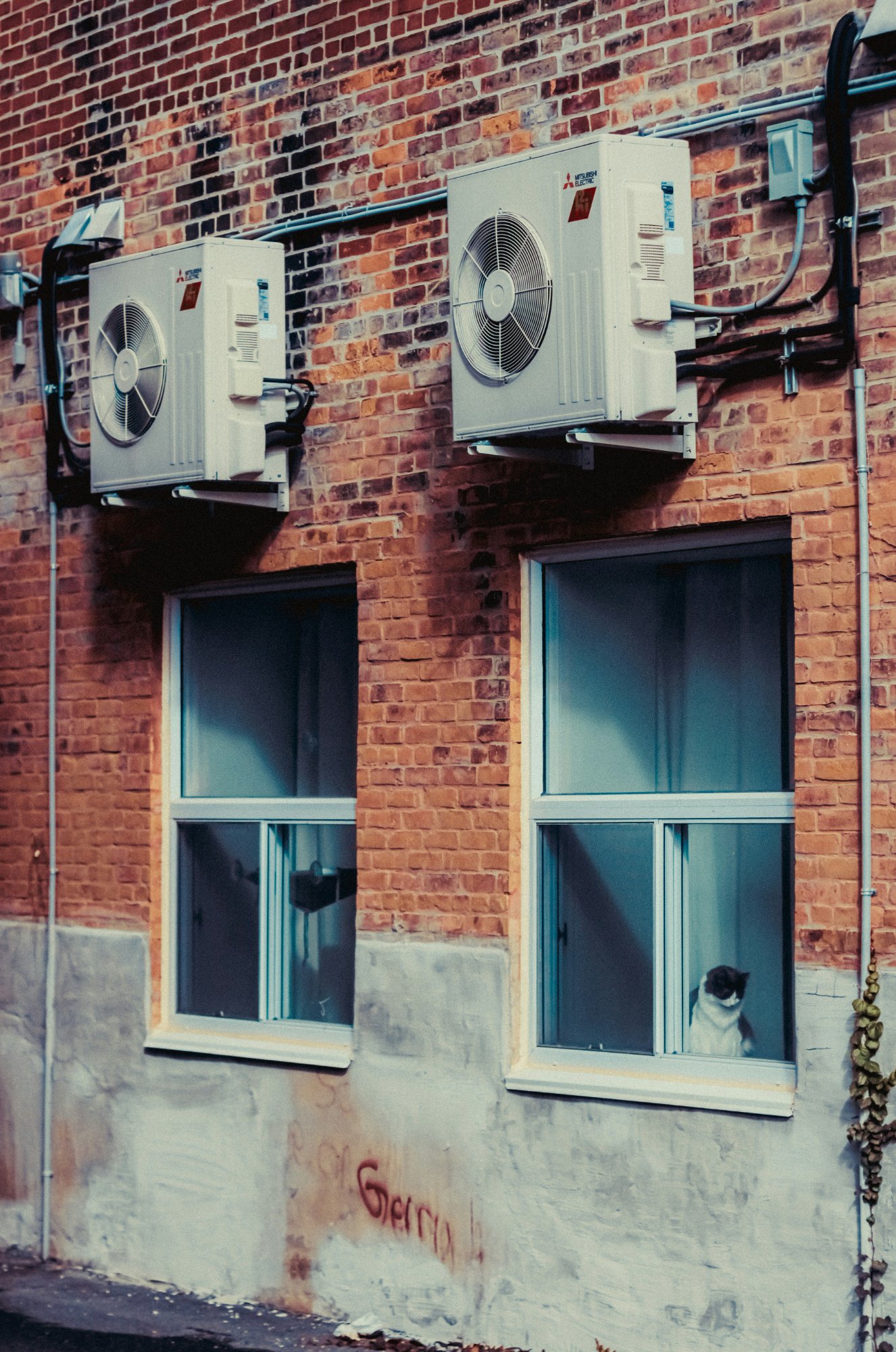 Mitsubishi split AC outdoor units on brick wall